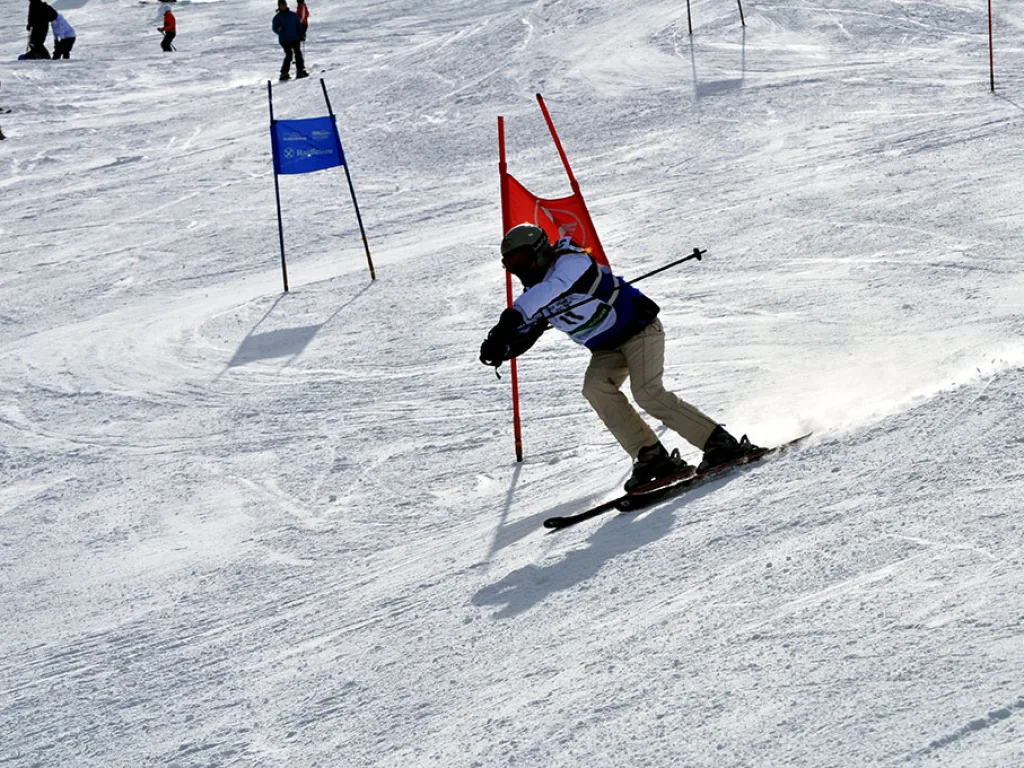 Snowboarder in tiefer Hocke zwischen rotem und blauem Tor.
